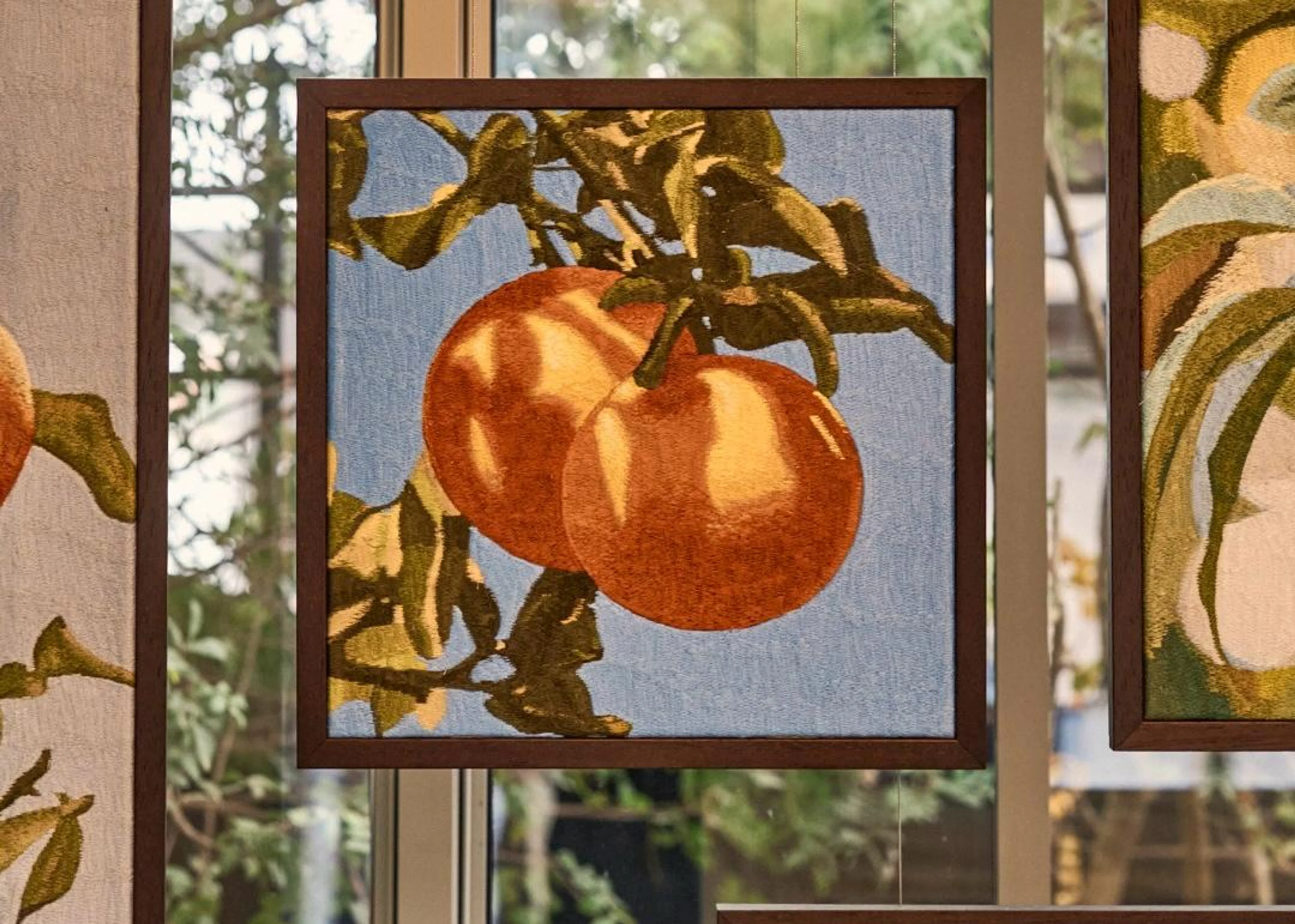 Ein quadratisch gerahmtes Kunstwerk des Künstlers Mustafa Boğa, das zwei reife Orangen an einem Zweig als detailreiche Stickerei zeigt.