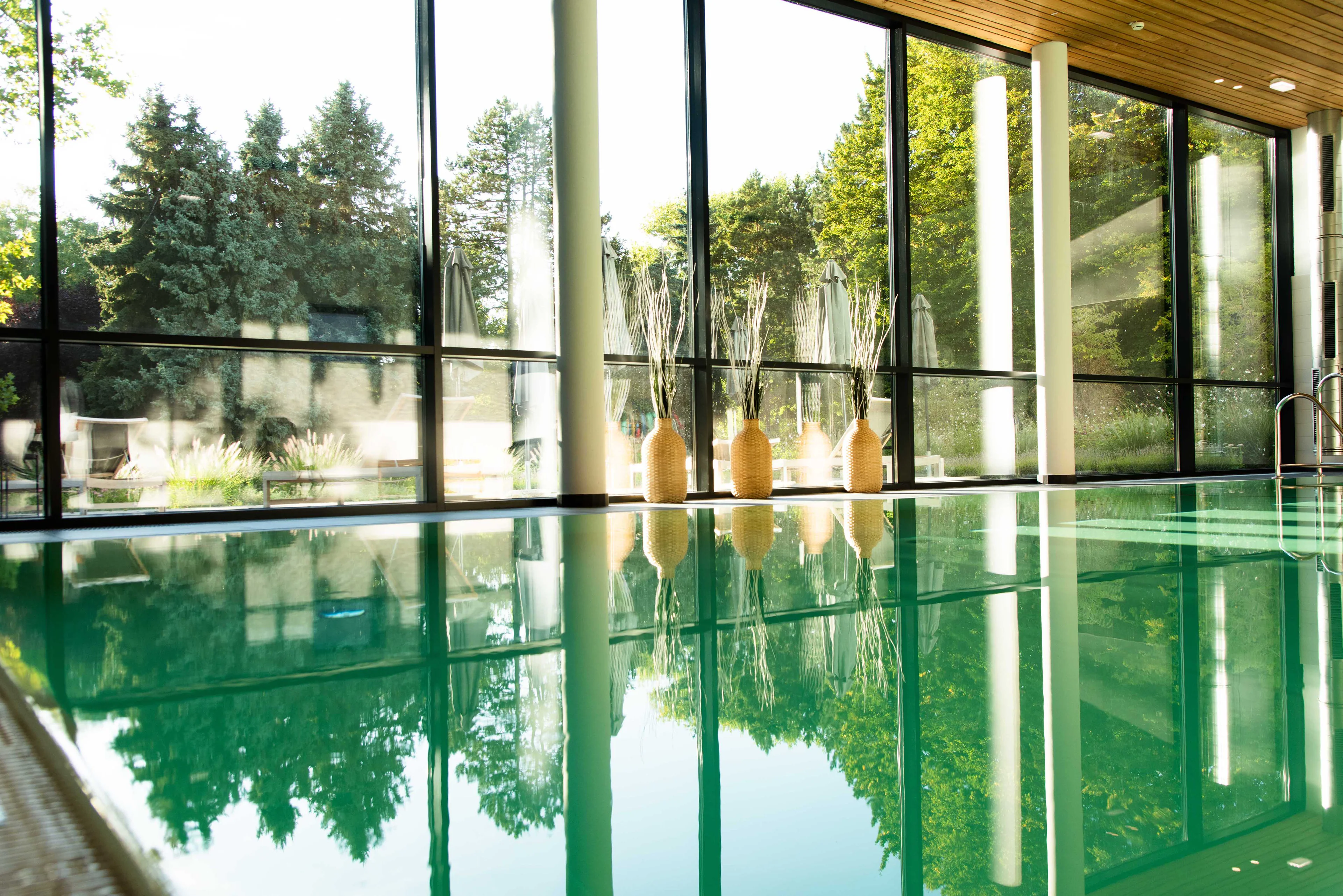 Innenpool eines Health Resorts mit großer Fensterfront und Blick auf die umliegende Natur.