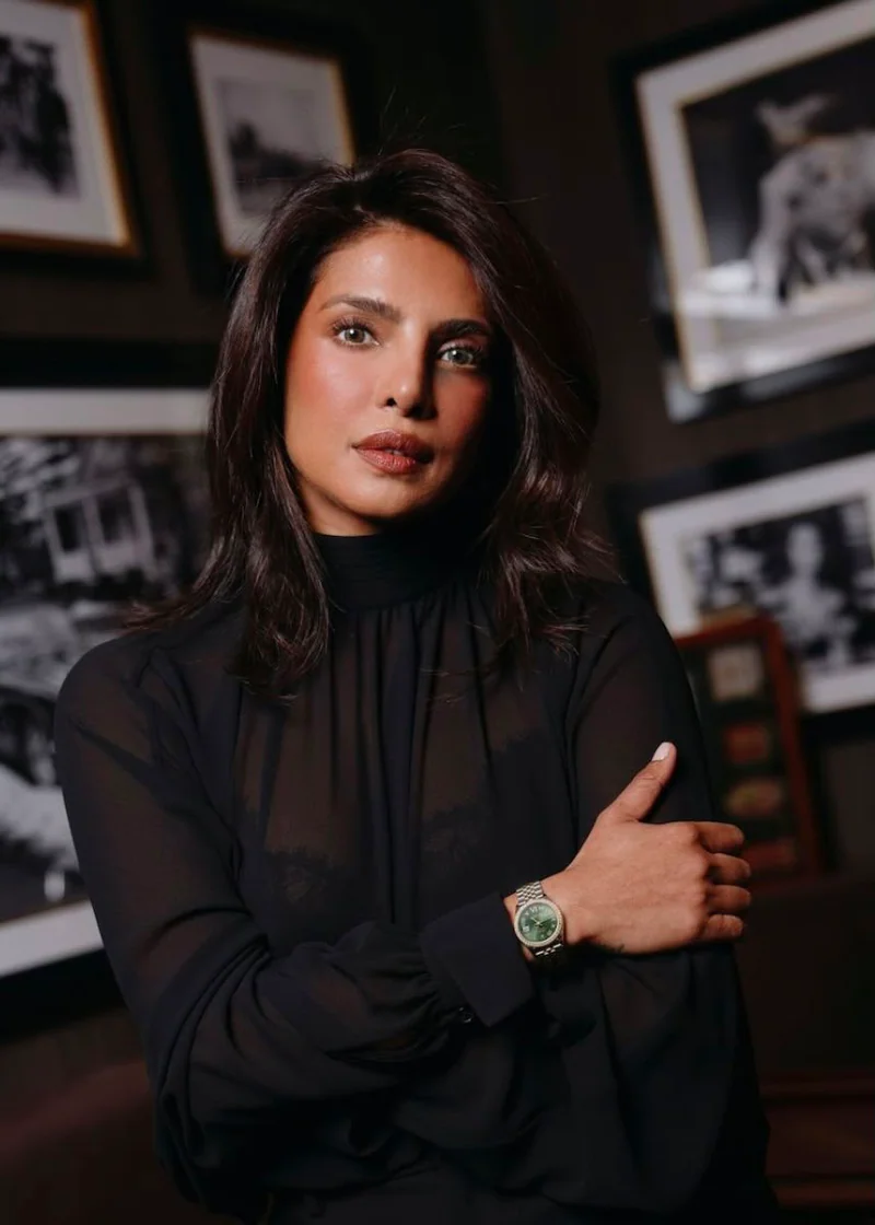 Priyanka Chopra Jonas mit schwarzer Bluse und Rolex-Armbanduhr am Handgelenk.