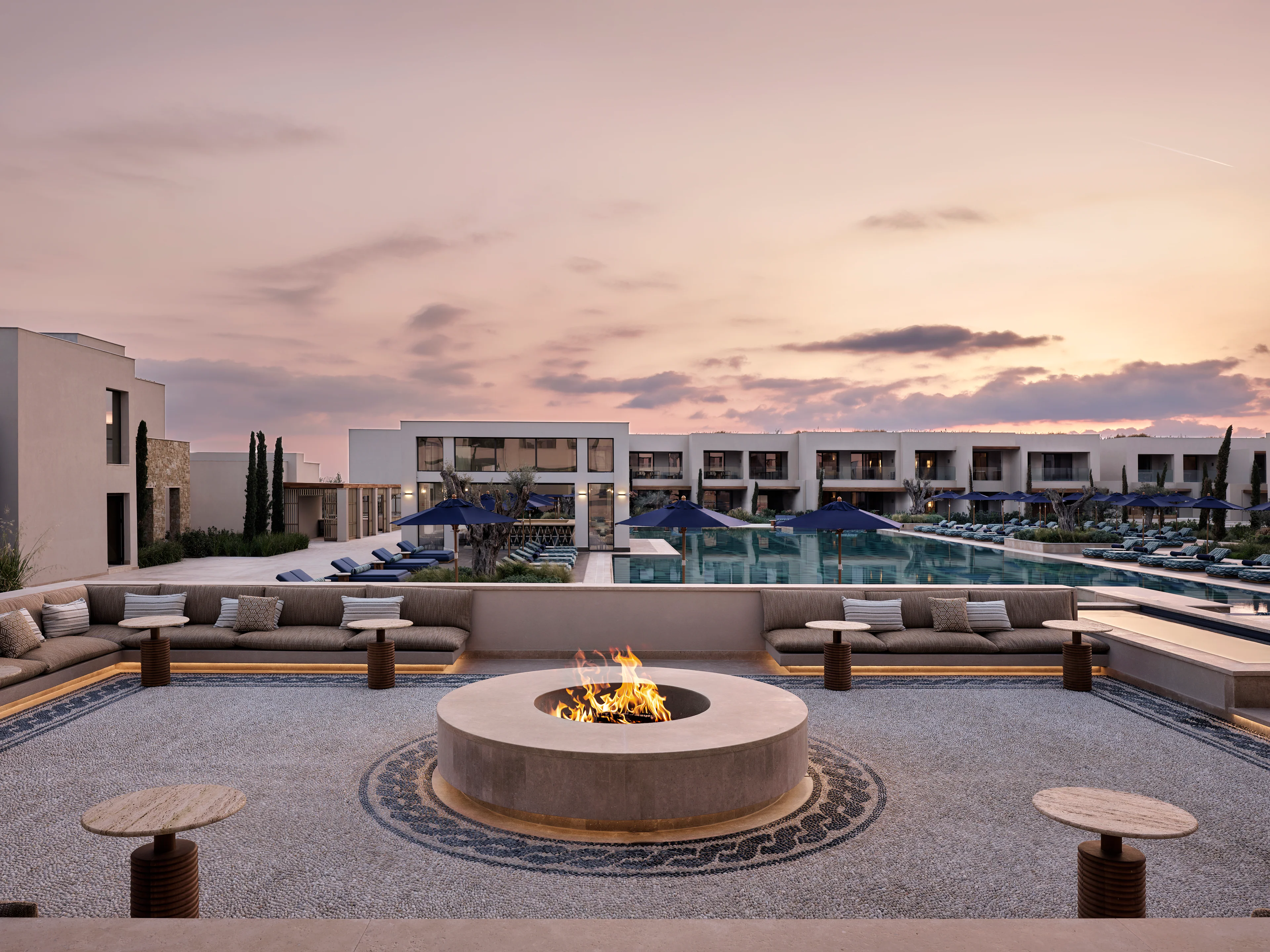 Terrasse mit Feuerstelle und Pool im AMOH Luxury Collection Resort auf Rhodos, im Hintergrund das Hotelgebäude.