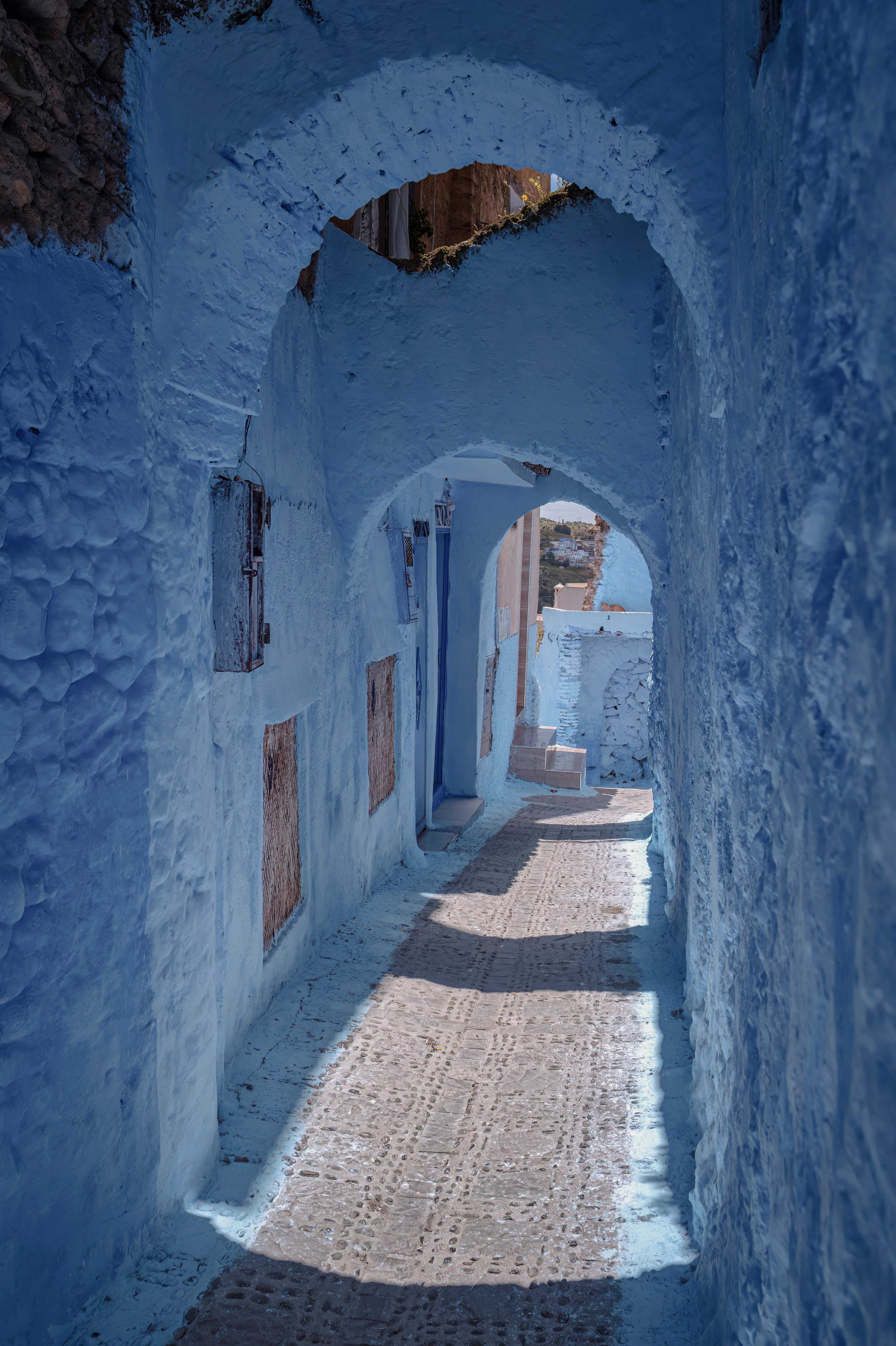 Blau getünchte Gasse mit traditionellen Torbögen in Chefchaouen, der berühmten Blauen Stadt im Rif-Gebirge in Marokko.