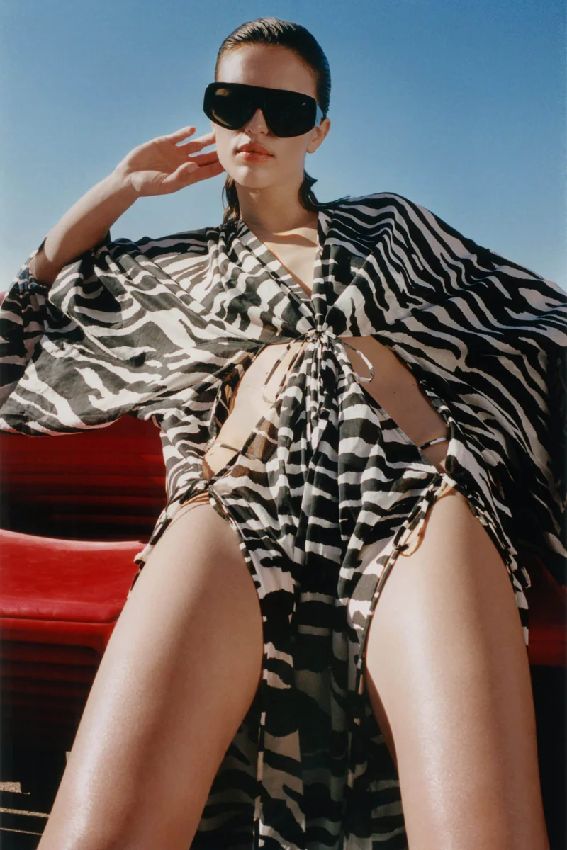 Model in schwarz-weißem Zebra-Print Kaftan über Swimwear mit Oversize-Sonnenbrille von The Attico