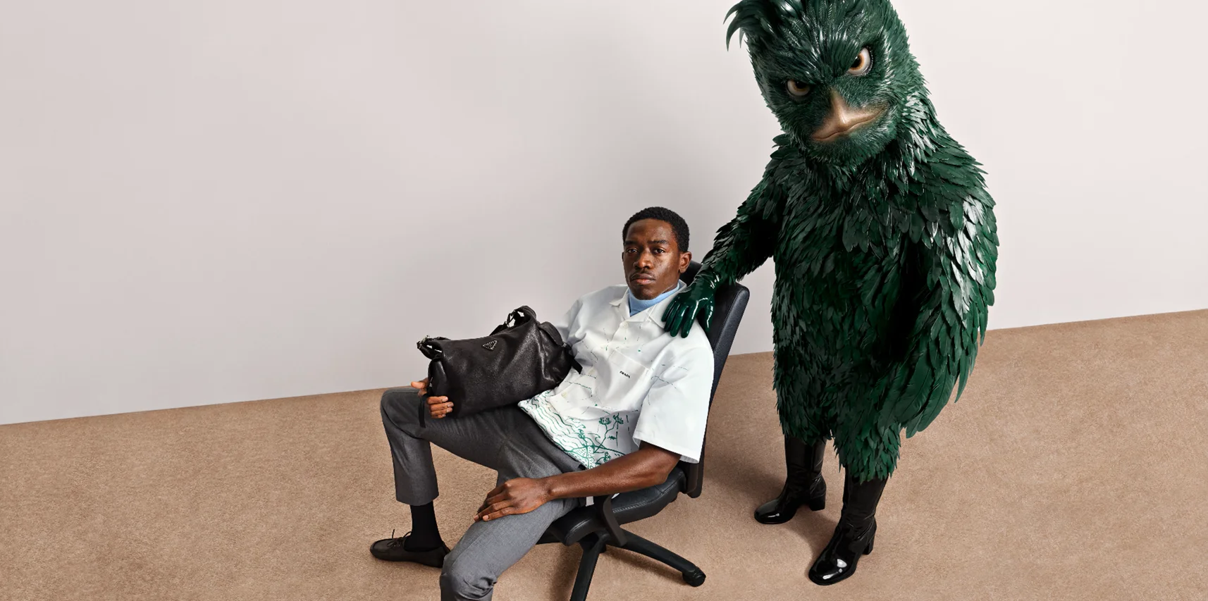Model mit schwarzer Prada Tasche neben grüner Vogel-Figur aus der Jordan Wolfson