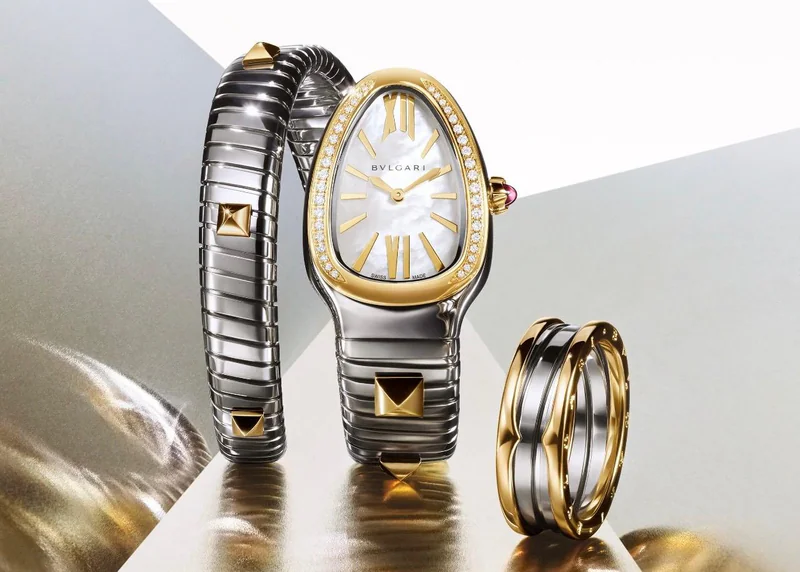 Eine Bulgari Serpenti Tubogas Damenuhr aus Gold und Edelstahl mit Diamanten neben einem passenden Bulgari-Ring.