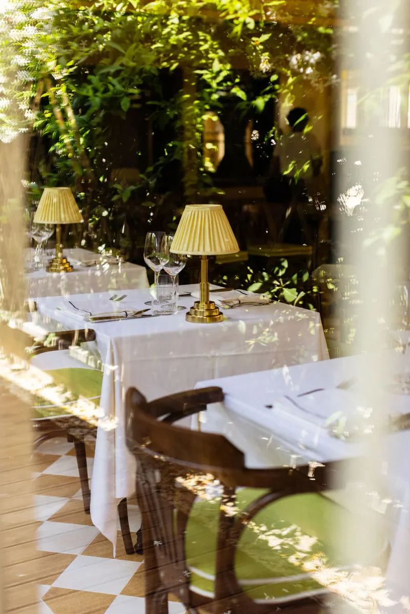 Restaurantterrasse des Da Giacomo Marechiaro Beach Clubs mit eleganten Tischen im Grünen.