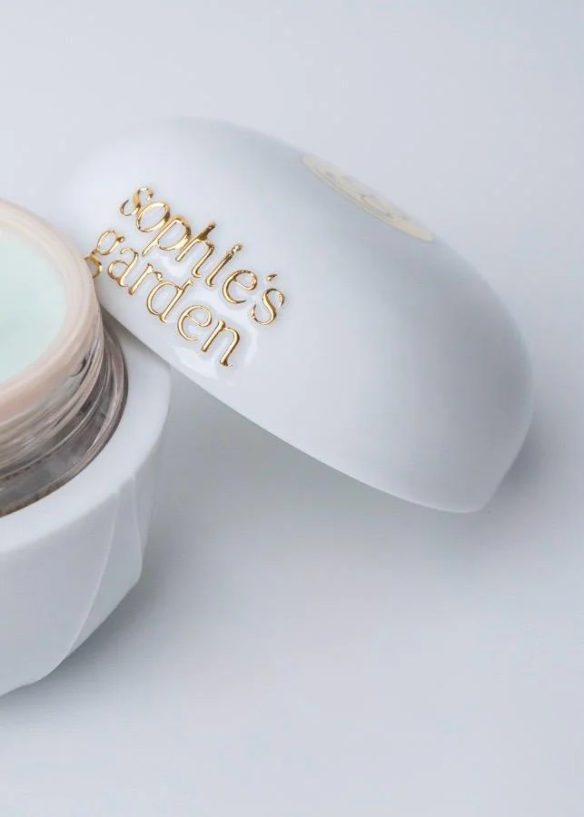 Sophie’s Garden Crème Phyto Cellulaire Luxustiegel Geöffneter weißer Porzellantiegel der Crème Phyto Cellulaire von Sophie's Garden mit hellgrüner Textur und goldenem Schriftzug auf dem Deckel vor weißem Hintergrund.