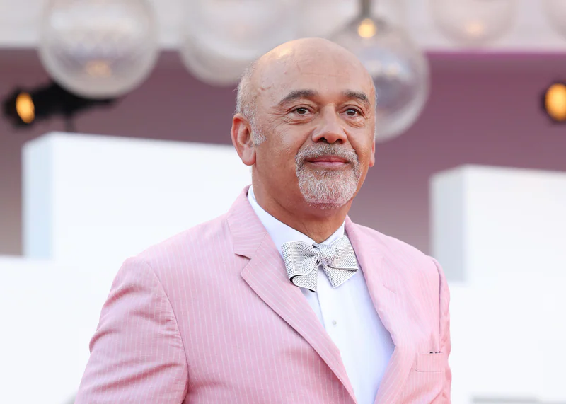 Christian Louboutin bei der Premiere von „Bones and All“ auf dem 79. Filmfestival von Venedig 2022 in einem rosa Nadelstreifenanzug mit Fliege.