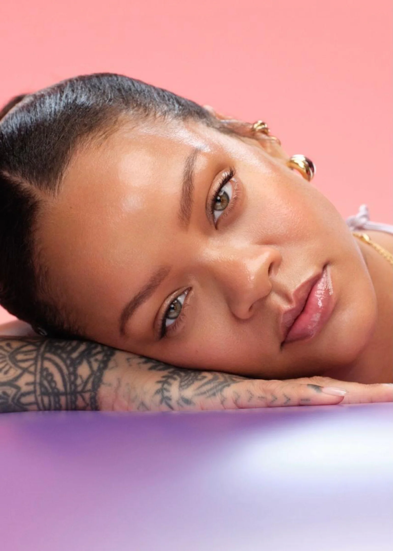 Fenty Beauty: Beauty-Look mit strahlendem Teint in Rosa Fenty-Beauty-Beauty-Look mit strahlendem Teint vor rosafarbenem Hintergrund
