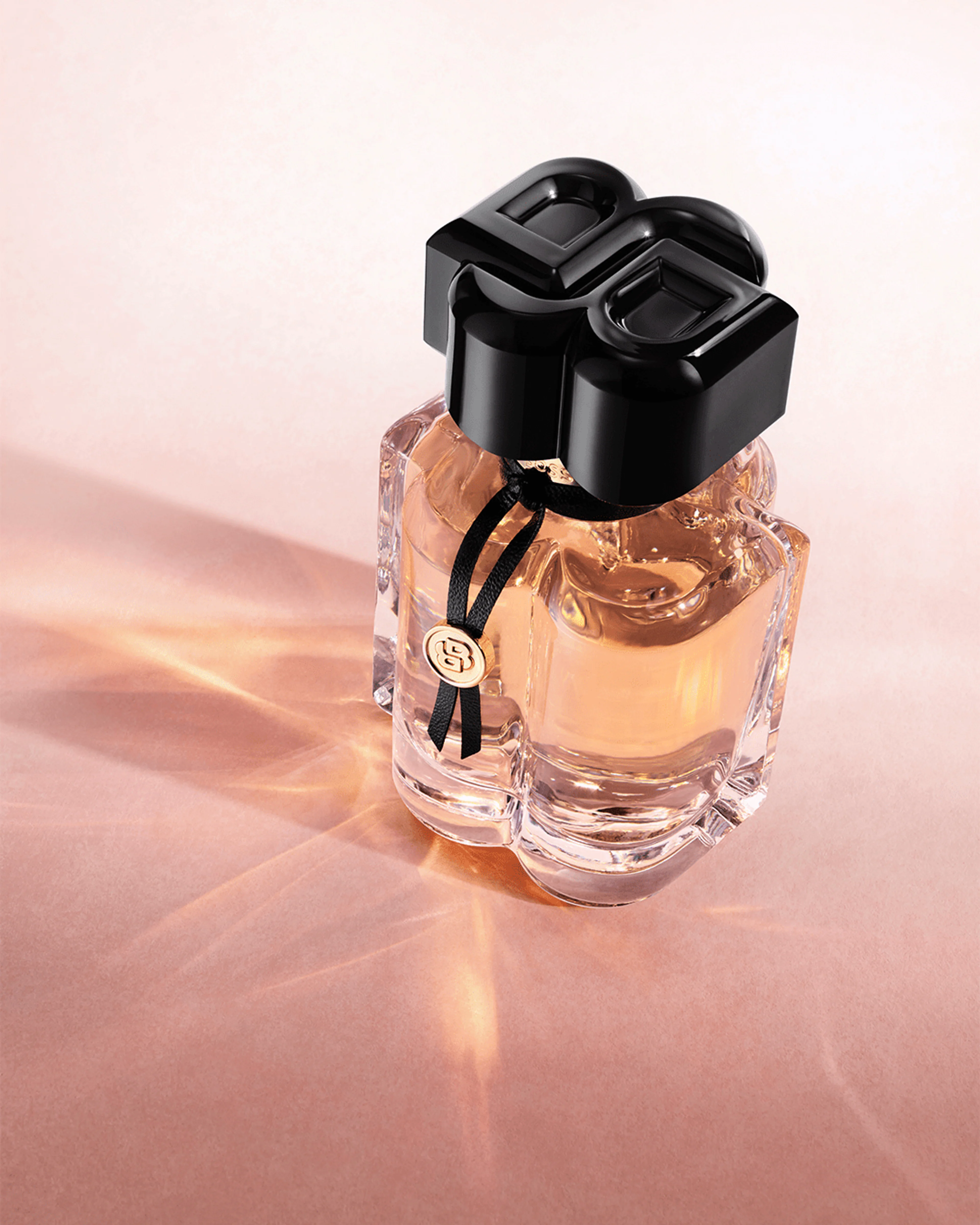 Flakon von Boss Bottled Beyond for Her Eau de Parfum mit ikonischem B-Verschluss auf roséfarbenem Hintergrund.