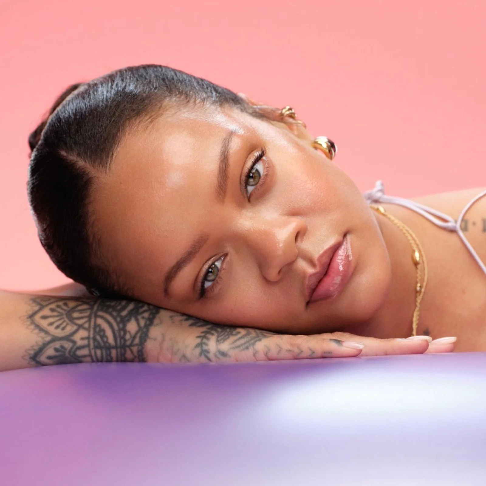 Fenty Beauty: Beauty-Look mit strahlendem Teint in Rosa Fenty-Beauty-Beauty-Look mit strahlendem Teint vor rosafarbenem Hintergrund