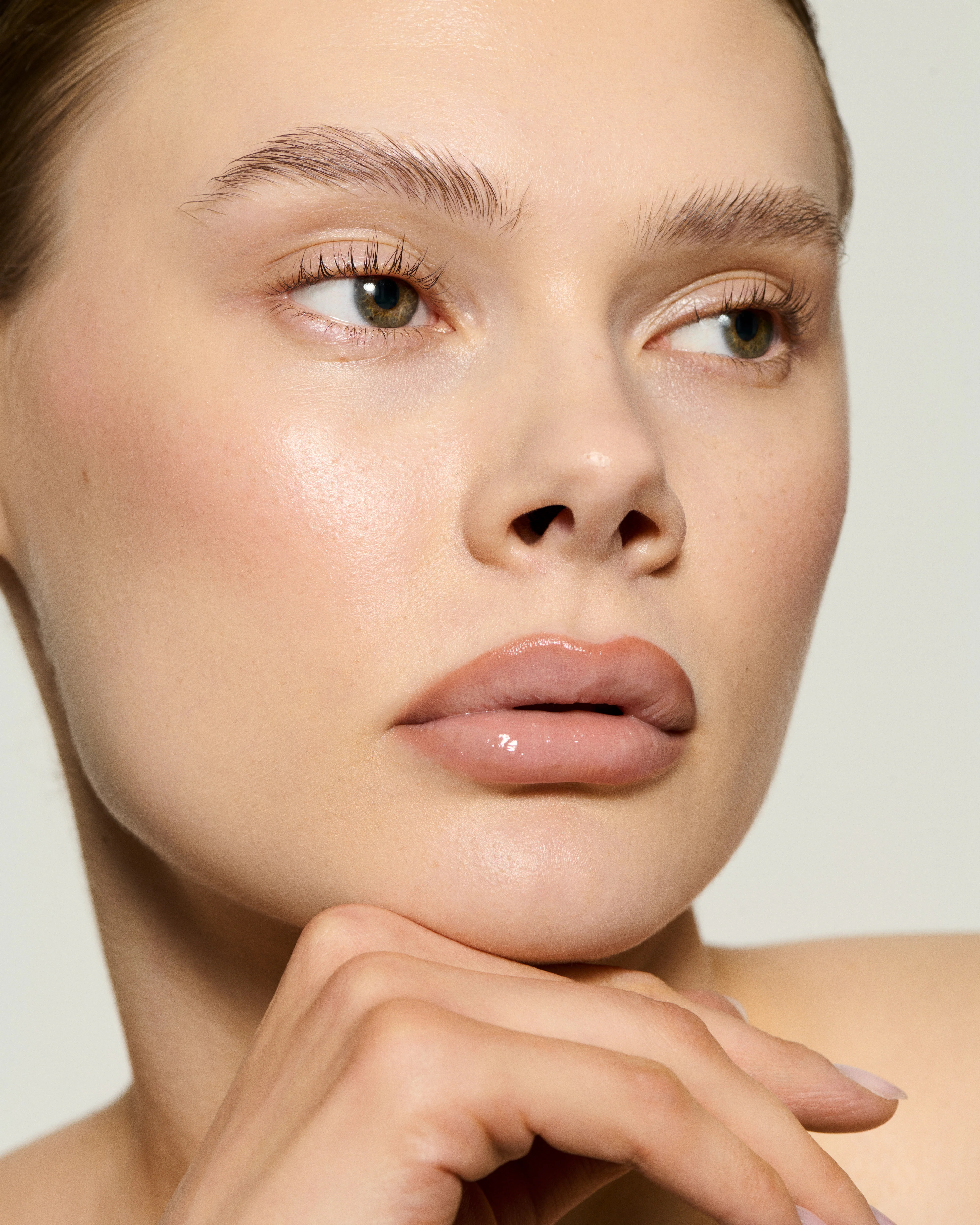 Model mit natürlichem Scandi-Glow-Make-up und Cushion Glaze Lip Gloss von Caia Cosmetics für glänzende Lippen und strahlende Haut