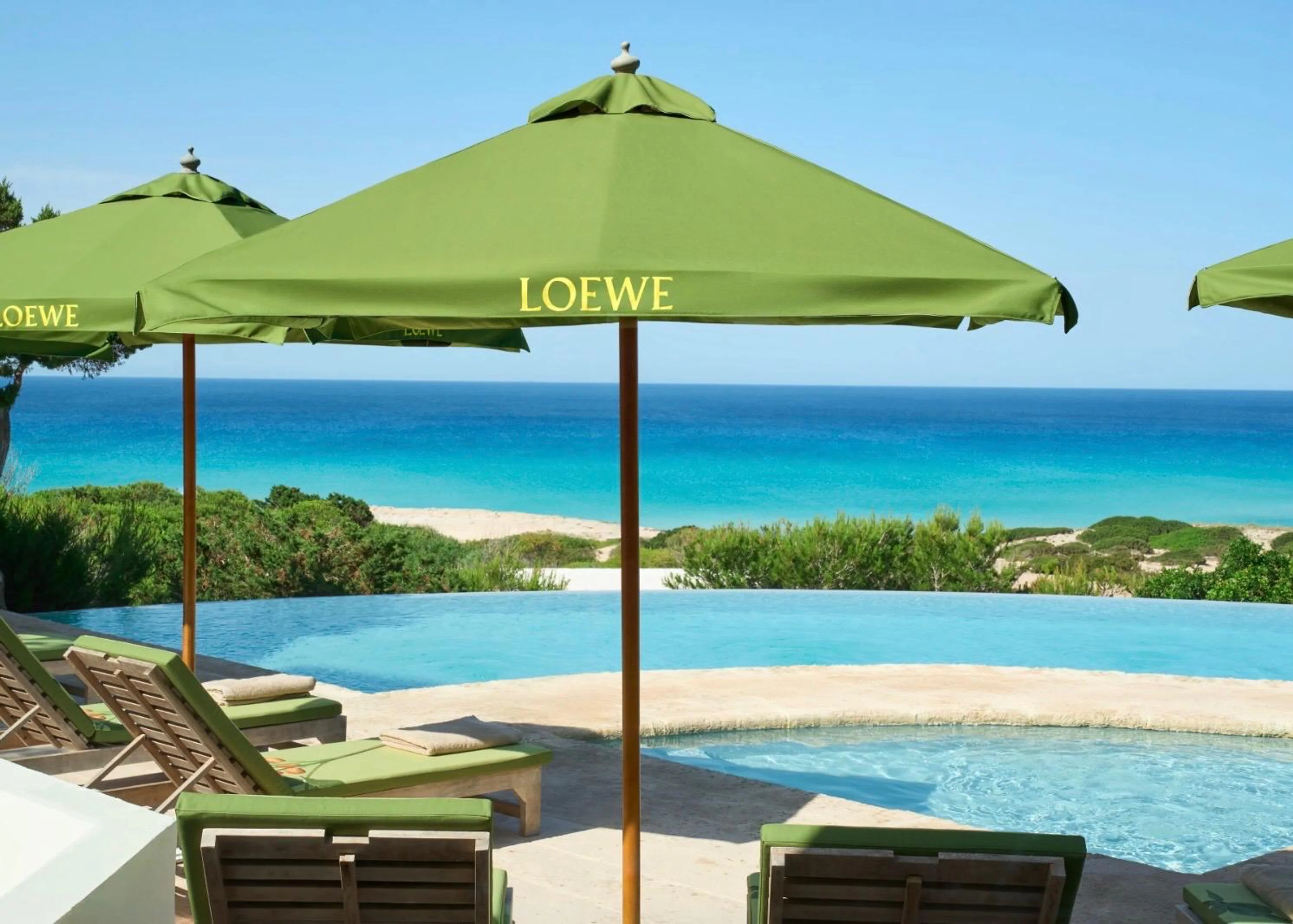 Grüner LOEWE-Sonnenschirm am Hotel Dunas de Formentera, wo Loewe Perfumes die neue Pistachio Duftkerze in einer sommerlichen Installation präsentiert.