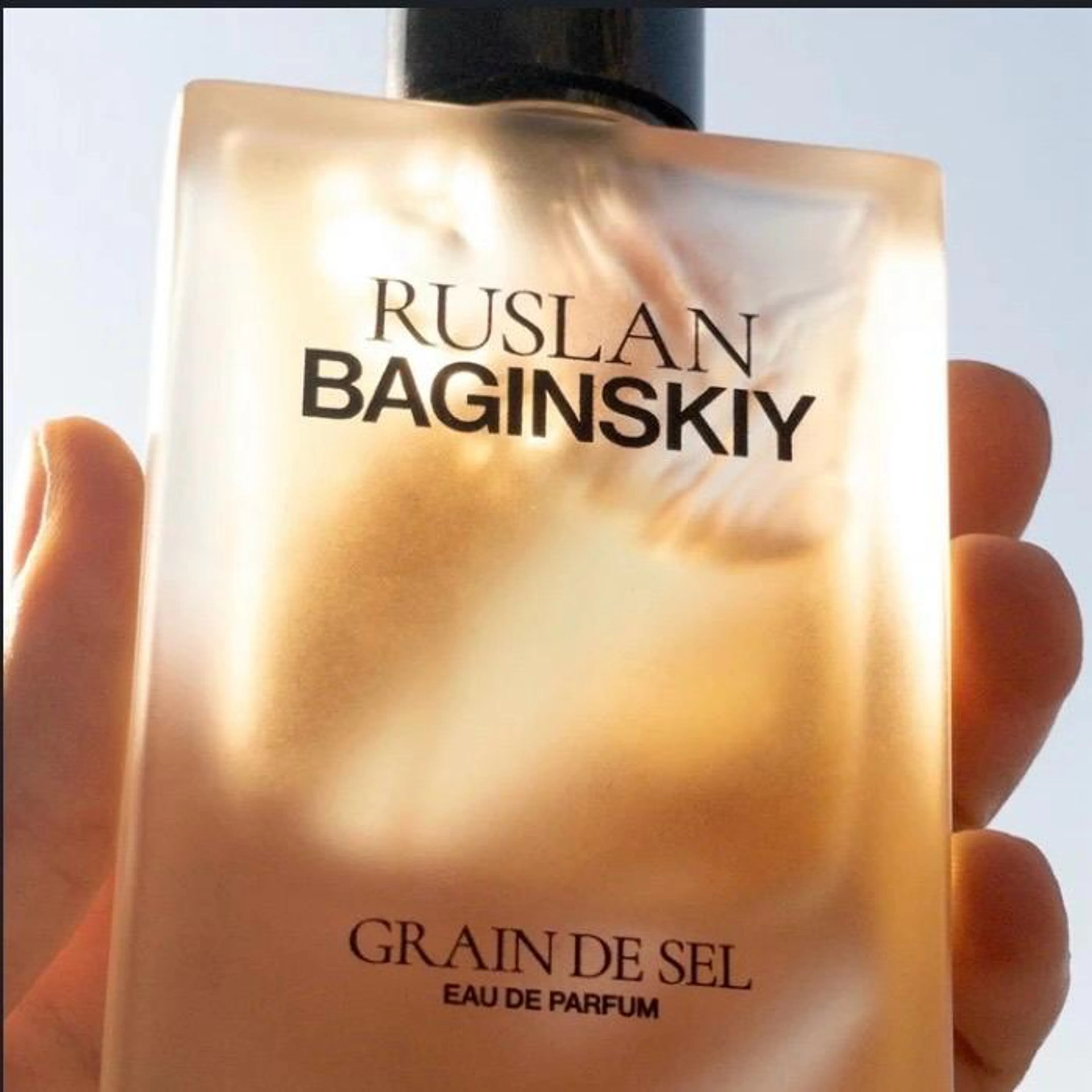 Hand hält das Parfum Grain de Sel von Ruslan Baginskiy vor hellem Hintergrund.