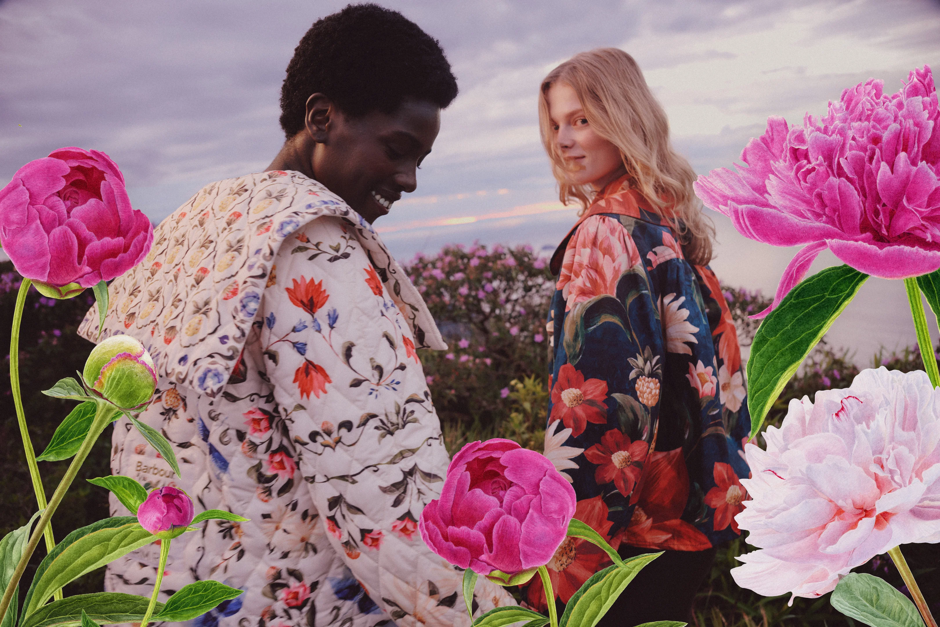 Zwei Models tragen florale Jacken aus der Barbour x Farm Rio Kollektion vor einer Blumenlandschaft.
