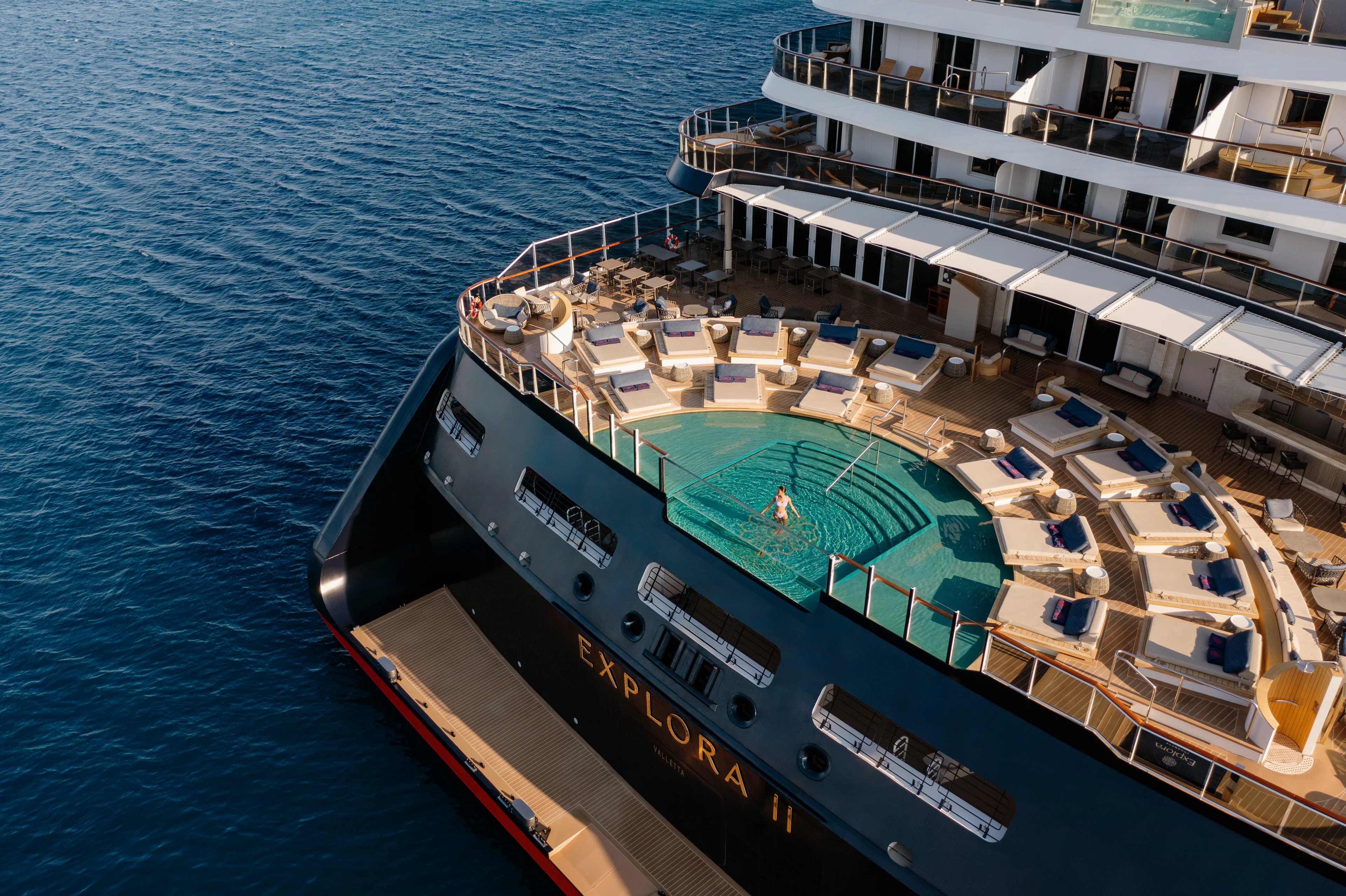 Pooldeck der EXPLORA I von Explora Journeys mit großzügigen Sonnenliegen und Blick auf das offene Meer