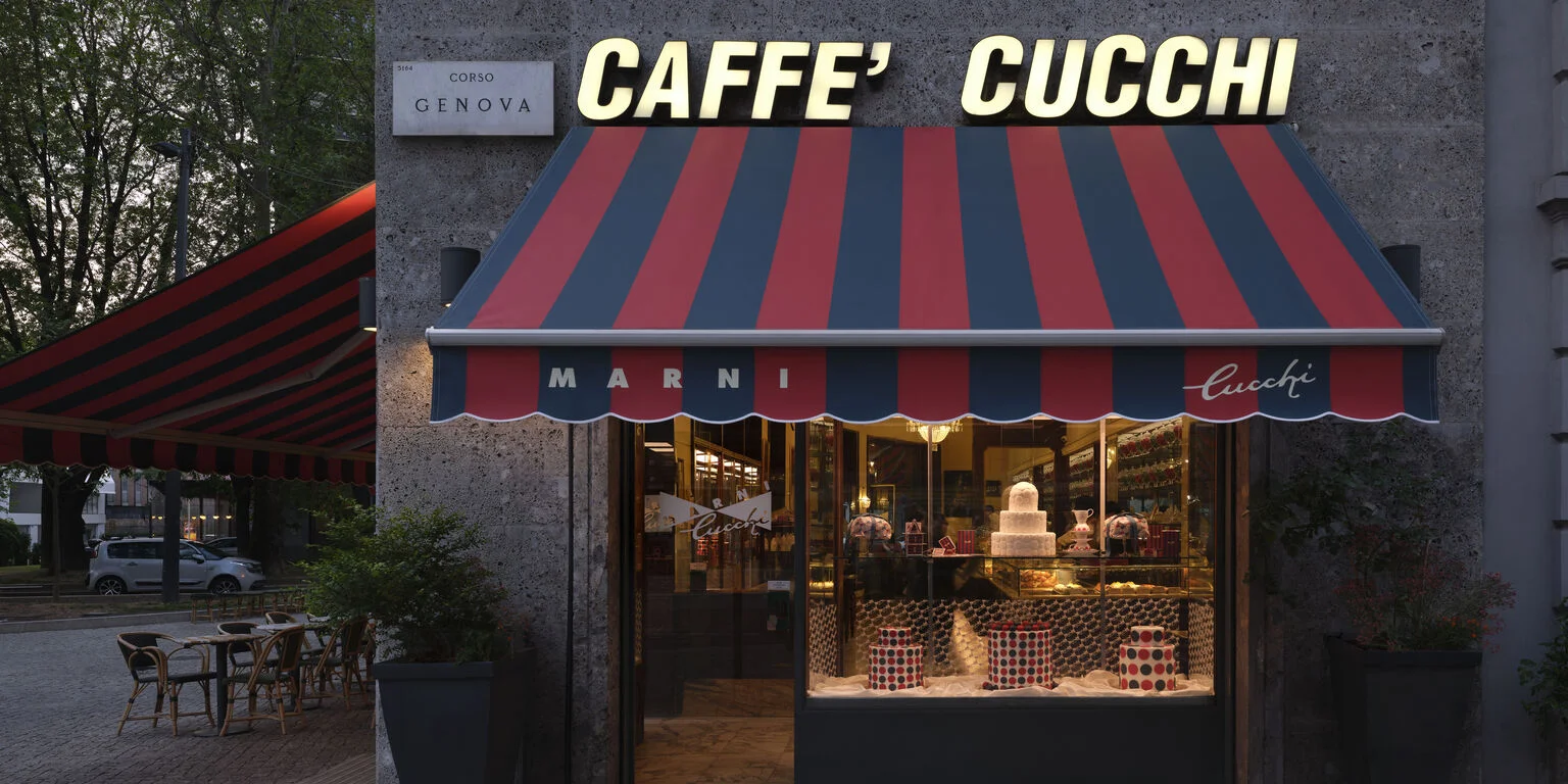 Marni gestaltet das historische Caffè Cucchi in Mailand zur Design Week mit rot-blau gestreifter Markise und beleuchtetem Schaufenster.