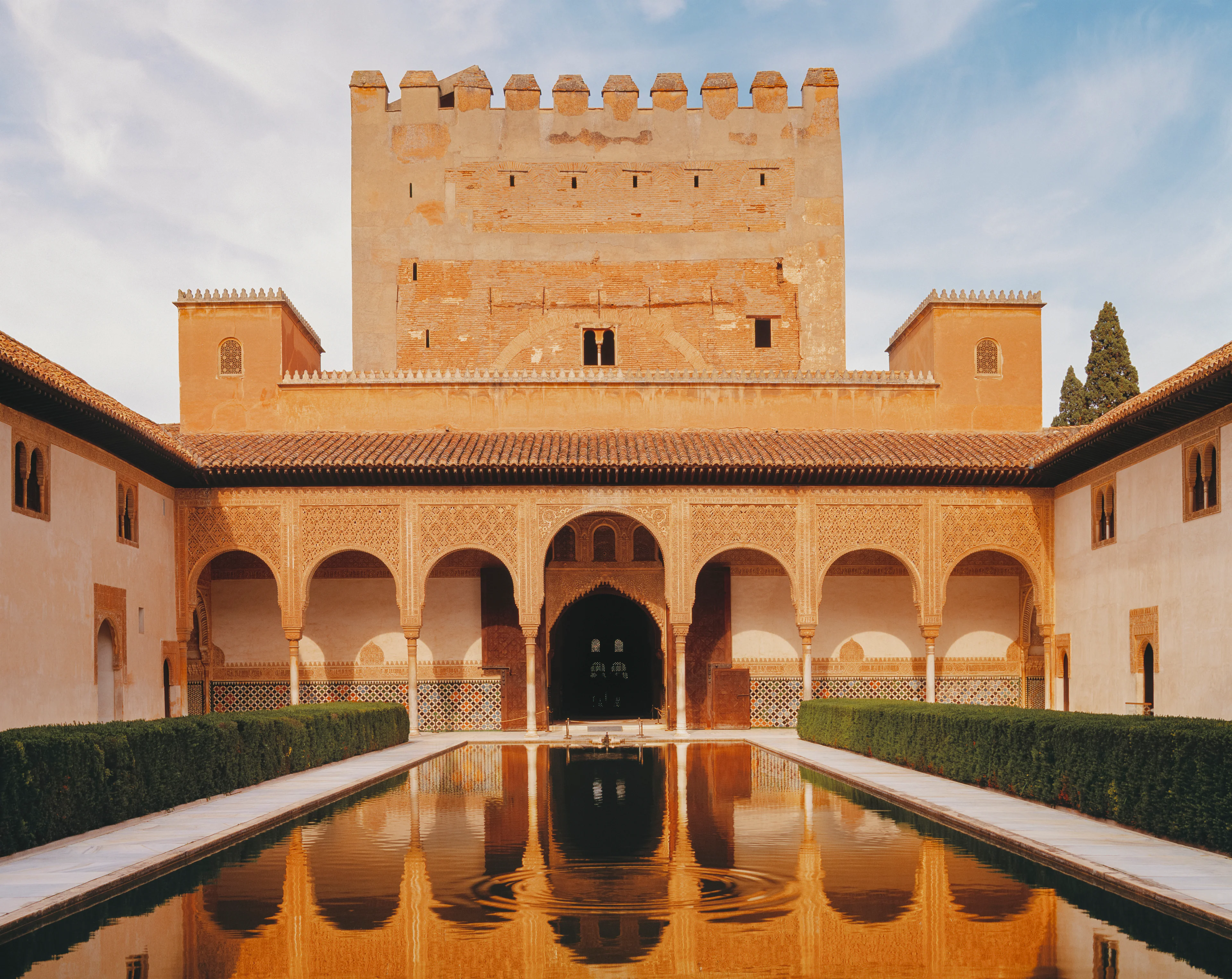 Blick auf den Innenhof der Alhambra in Granada mit maurischen Arkaden, spiegelndem Wasserbecken und historischer Architektur in Andalusien, Spanien.